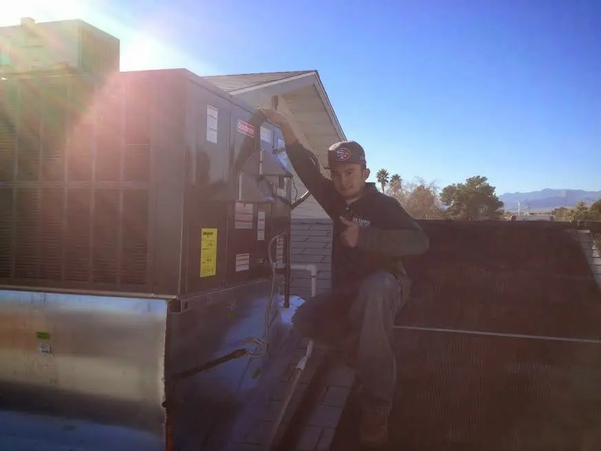 HVAC technician performing Heat Pump Repair on a rooftop unit in Corrales